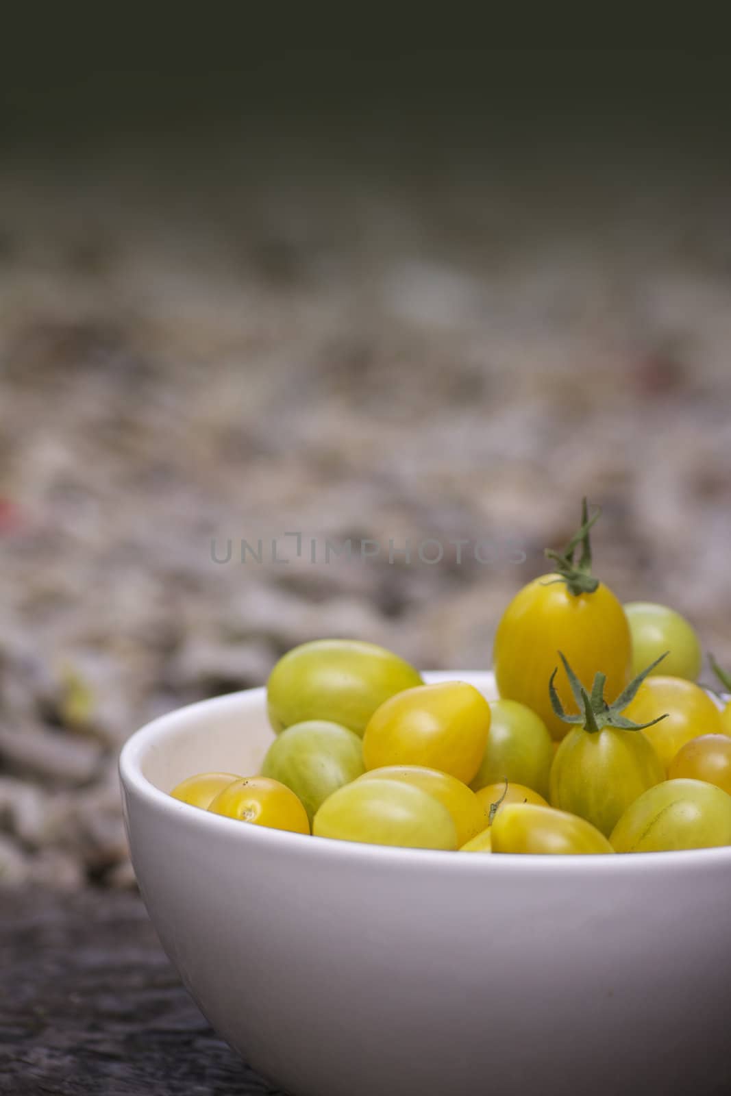 A bowl of pear shaped tomatoes in a white china bowl shot on a portrait format with room for copy etc above.