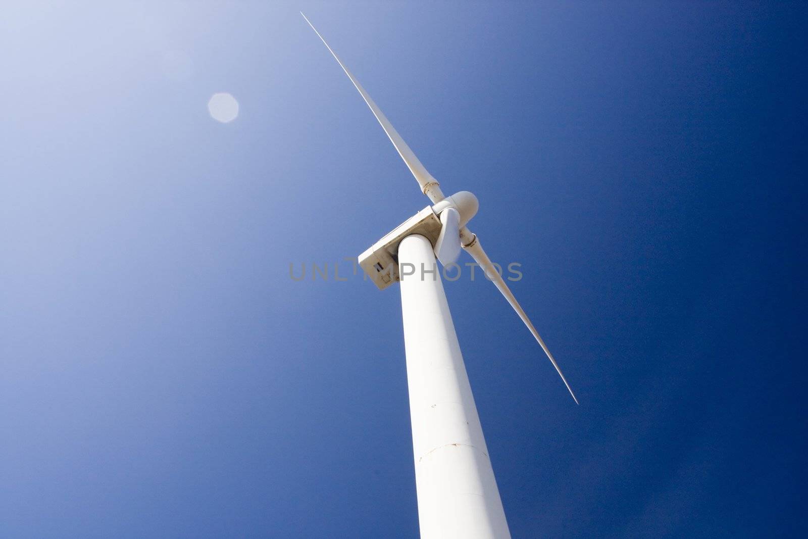 View of a wind generator tower over a blue sky.