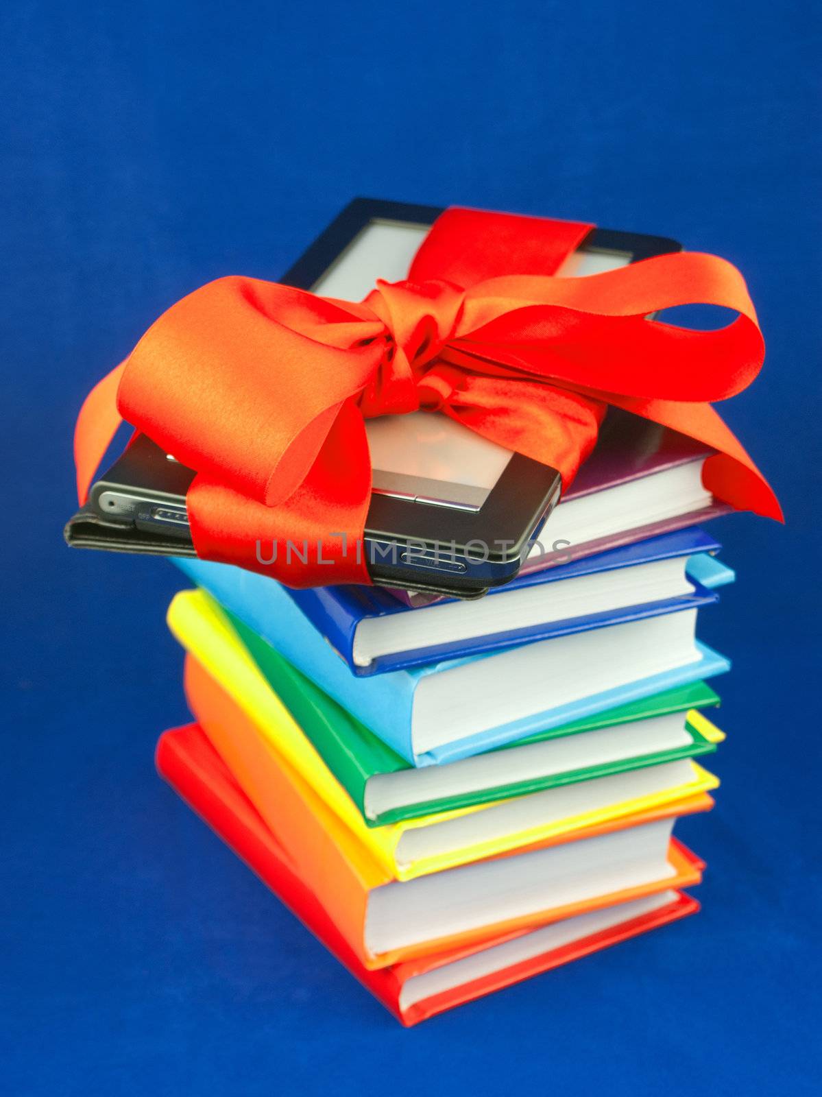 Electronic book reader tied up with red ribbon on the stack of books