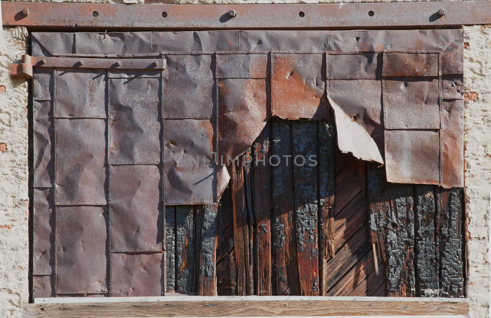 Old rusted worn and decaying steel covered wood door
