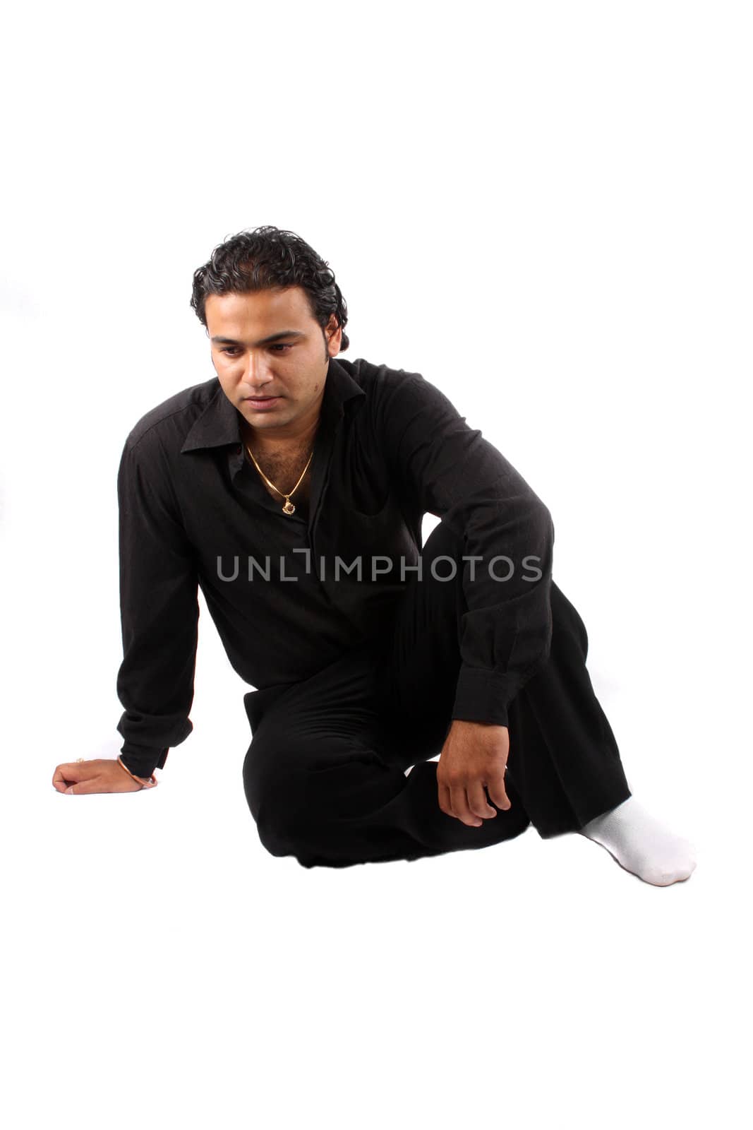 A depressed Indian guy sitting on the floor, on white studio background.