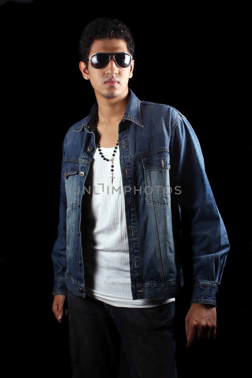 A handsome young Indian guy, on black studio background.