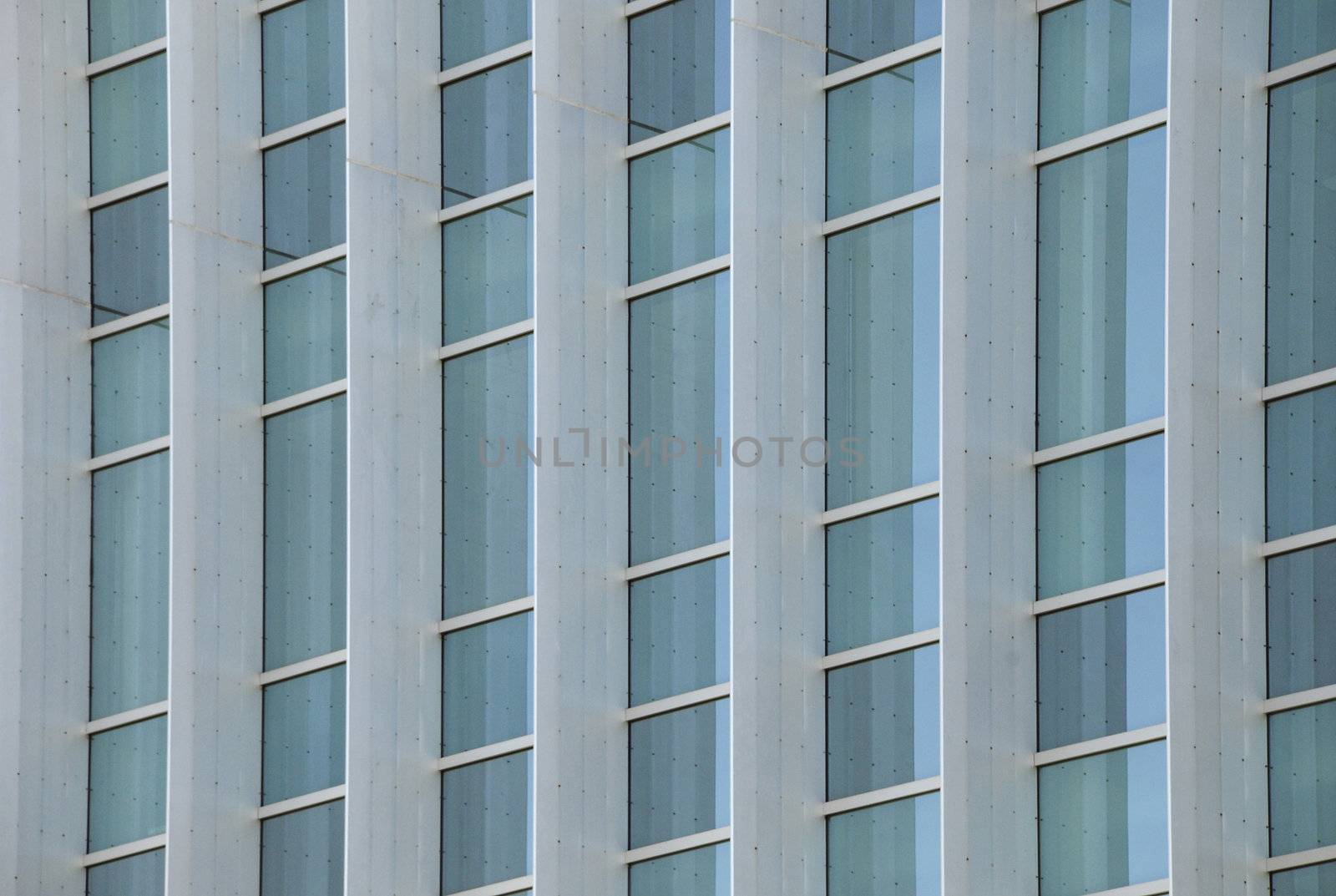 Exterior windows of a modern steel and glass commercial office building reflecting blue sky