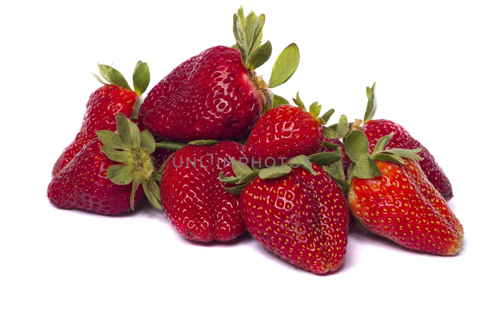 Close view of a pile of strawberry fruits isolated on a white background.