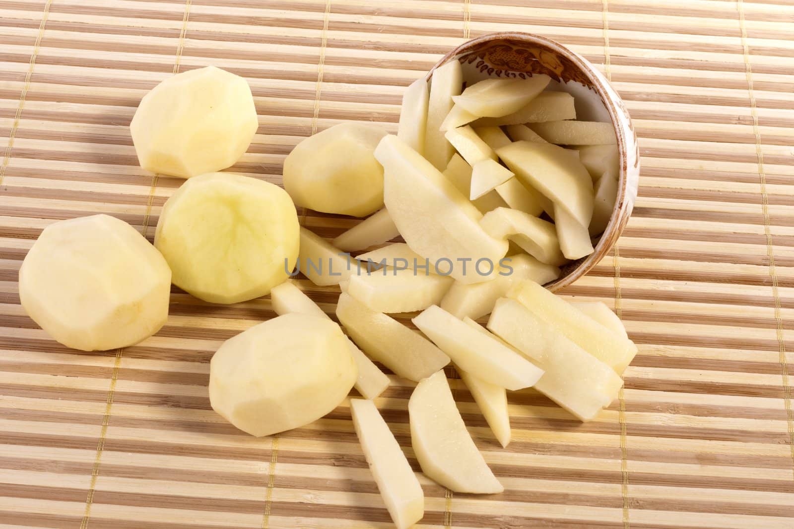 Close up view of some sliced potatoes isolated on bamboo background.