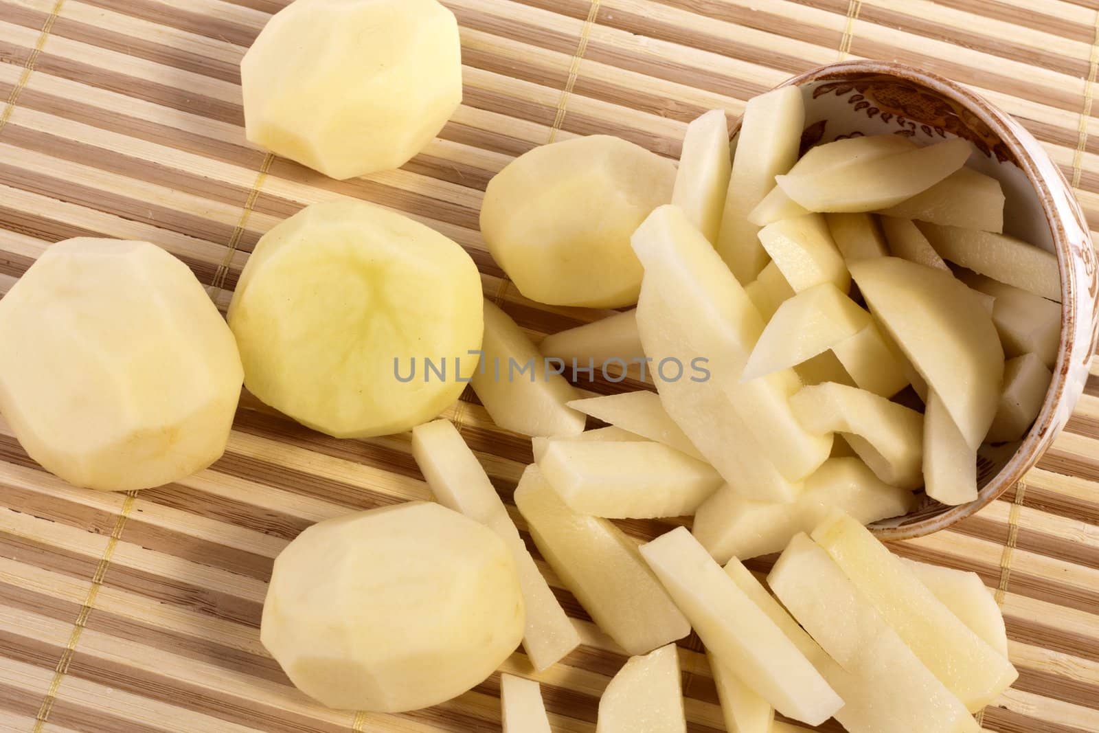 Close up view of some sliced potatoes isolated on bamboo background.