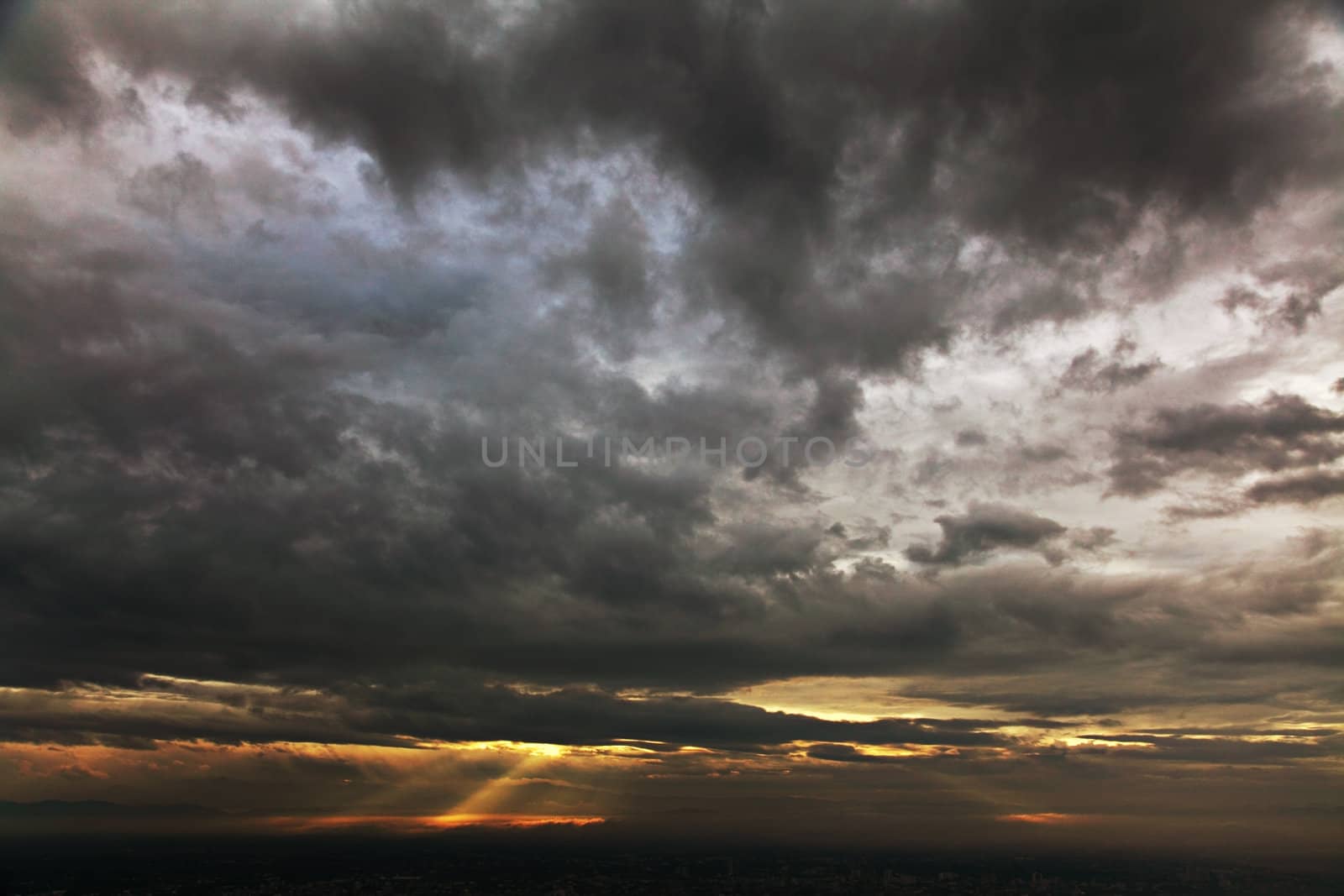 Dramatic sky of heavy gray clouds and sunbeams