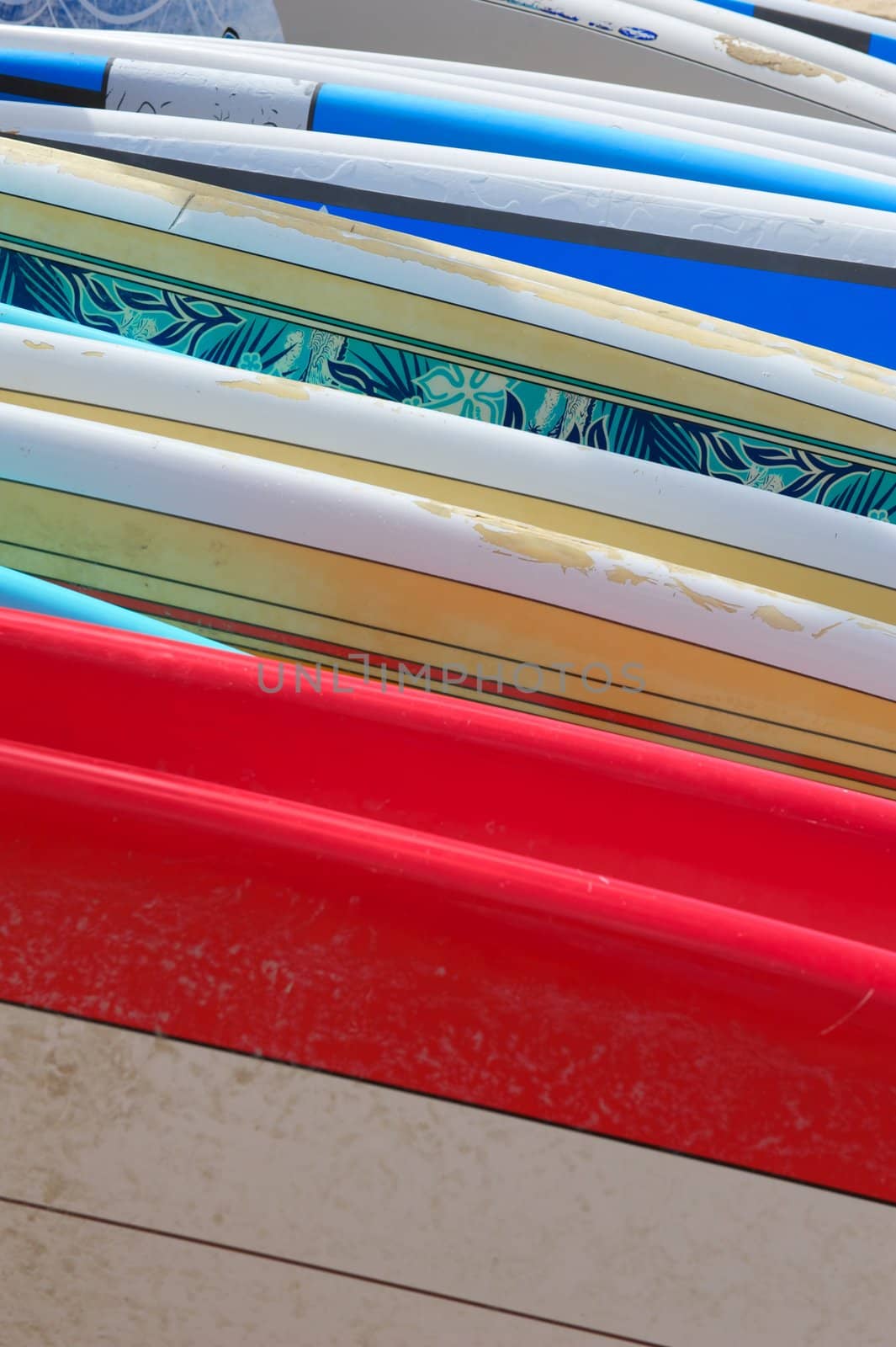A row of brightly colored renal surfboards laying on the sand in Hawaii