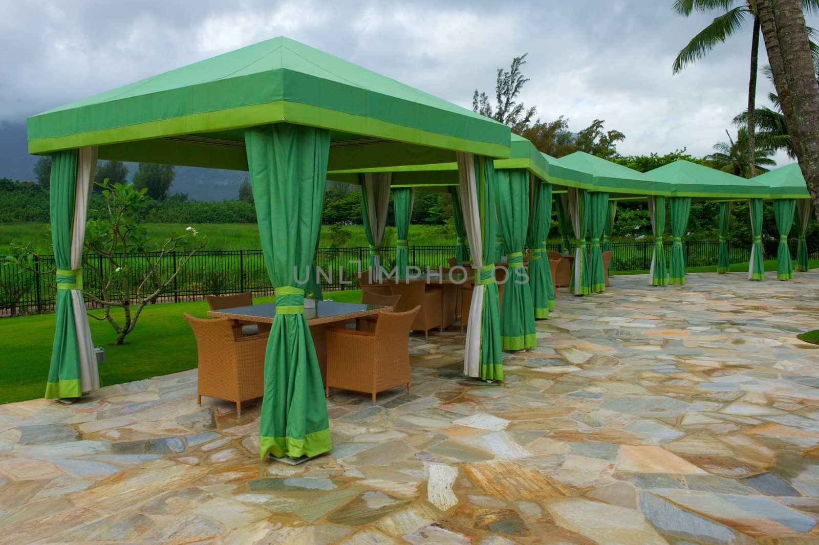 Verdant green shade structures or cabanas with tables and chairs at a resort in Hawaii