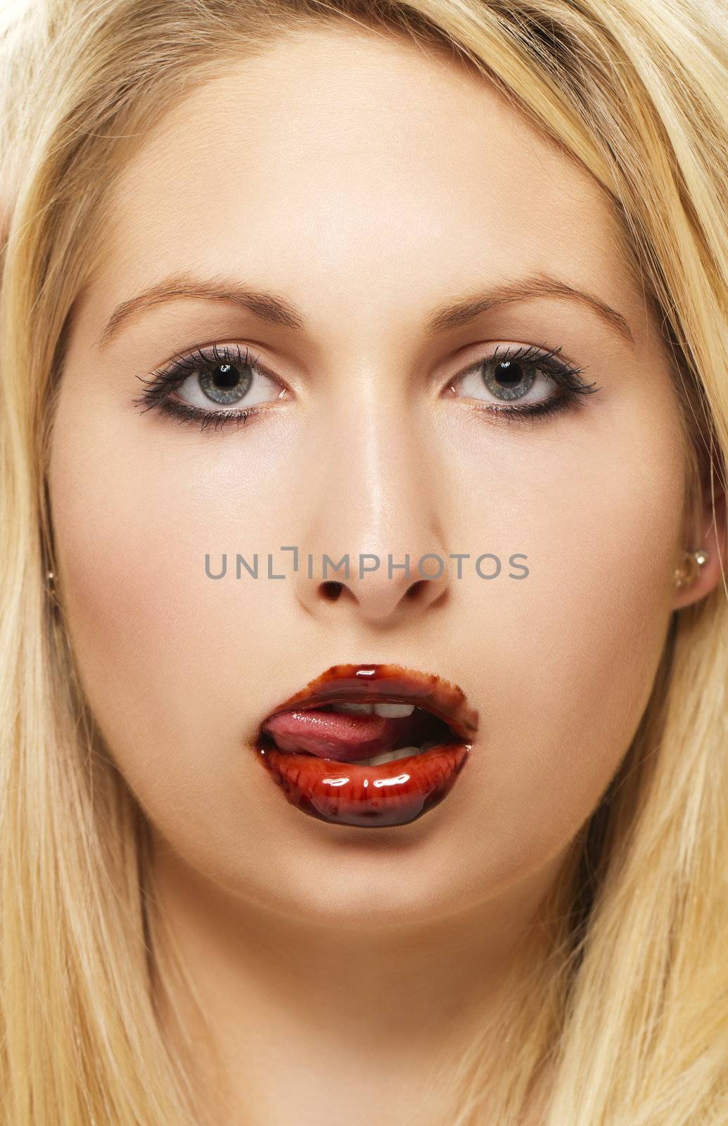 beautiful blonde woman licking chocolate from her chocolate covered lips on white background