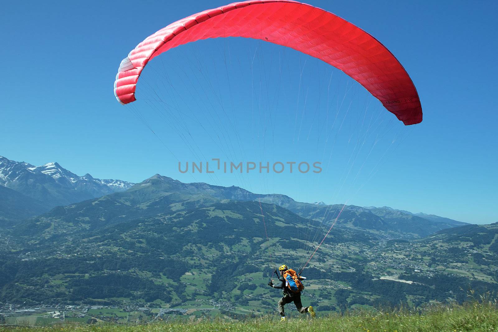 paraglider running for take-off in alpine mountain