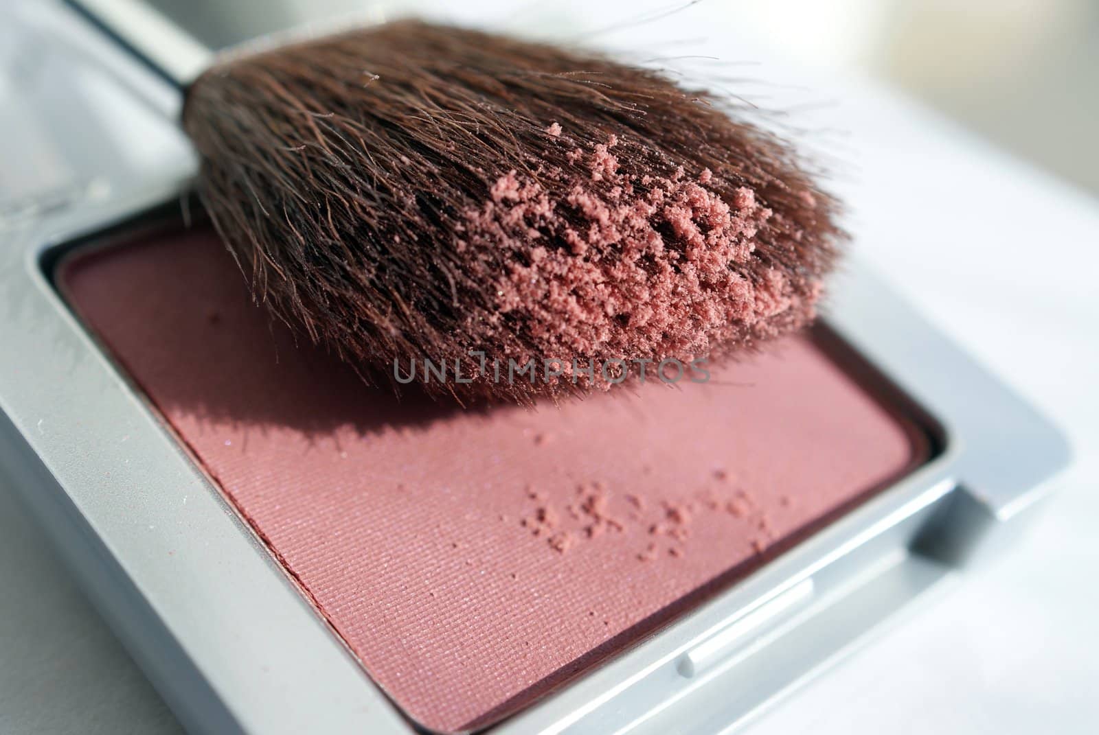 A macro shot of a blusher compact with a brush. Shallow depth of field.