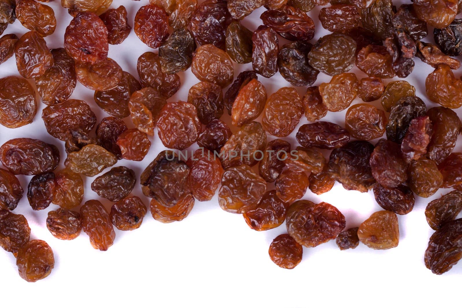 Close view of a pile of dry raisins isolated on a white background.