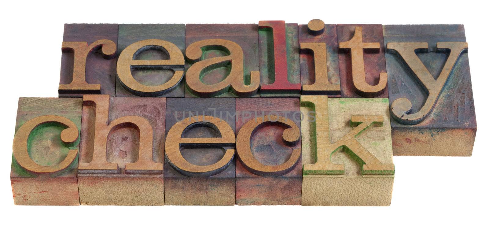 reality check concept  - words in  vintage wooden letterpress printing blocks, stained by color inks, isolated on white