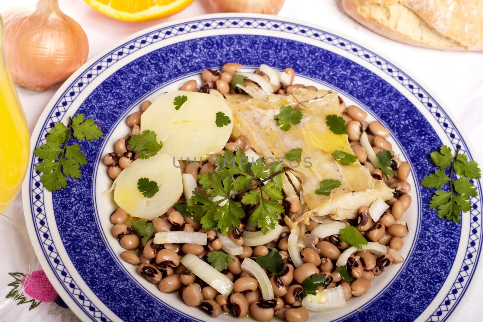 View of a meal with brown beans with cod and potatoes, tempered with olive oil and parsley.