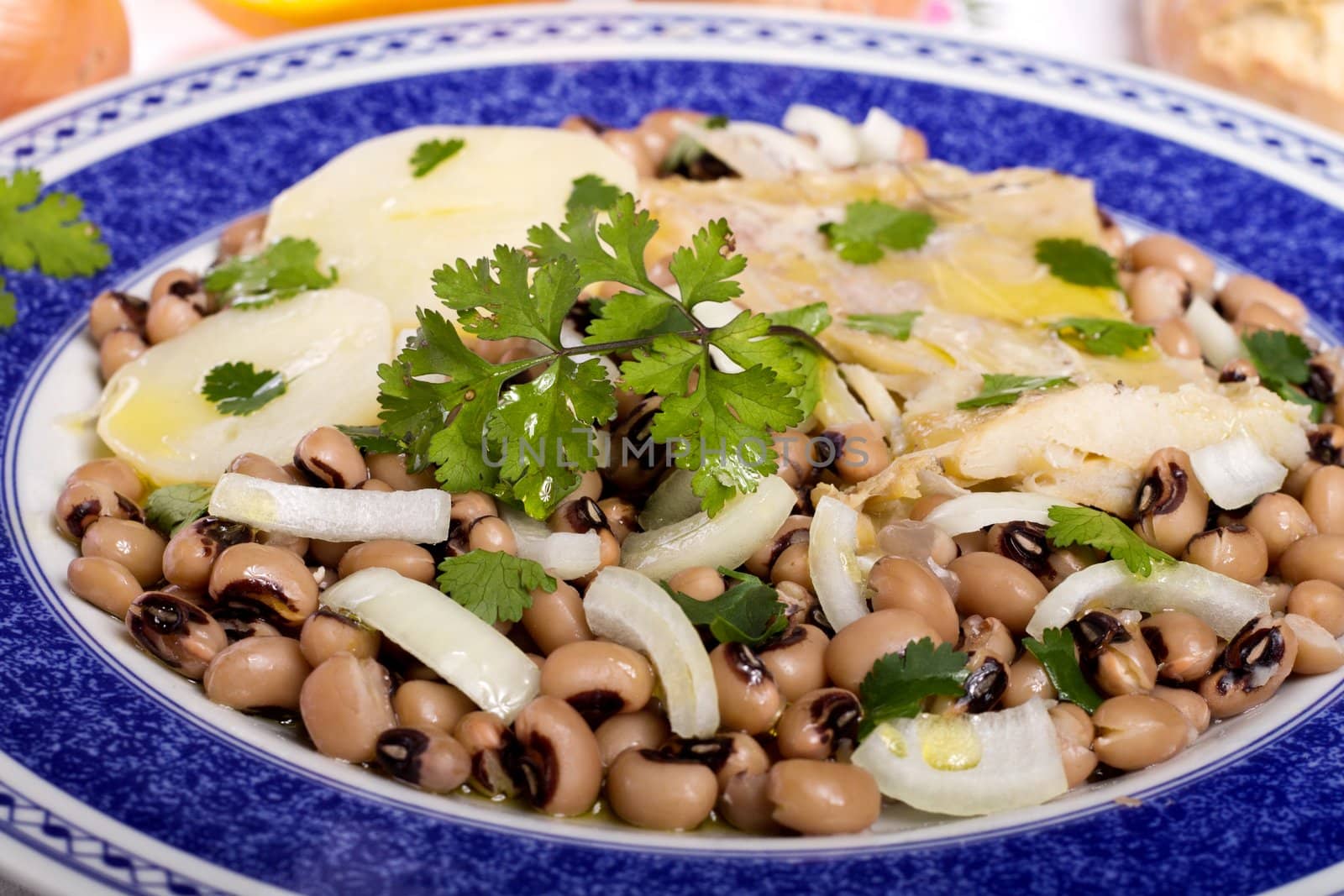 View of a meal with brown beans with cod and potatoes, tempered with olive oil and parsley.