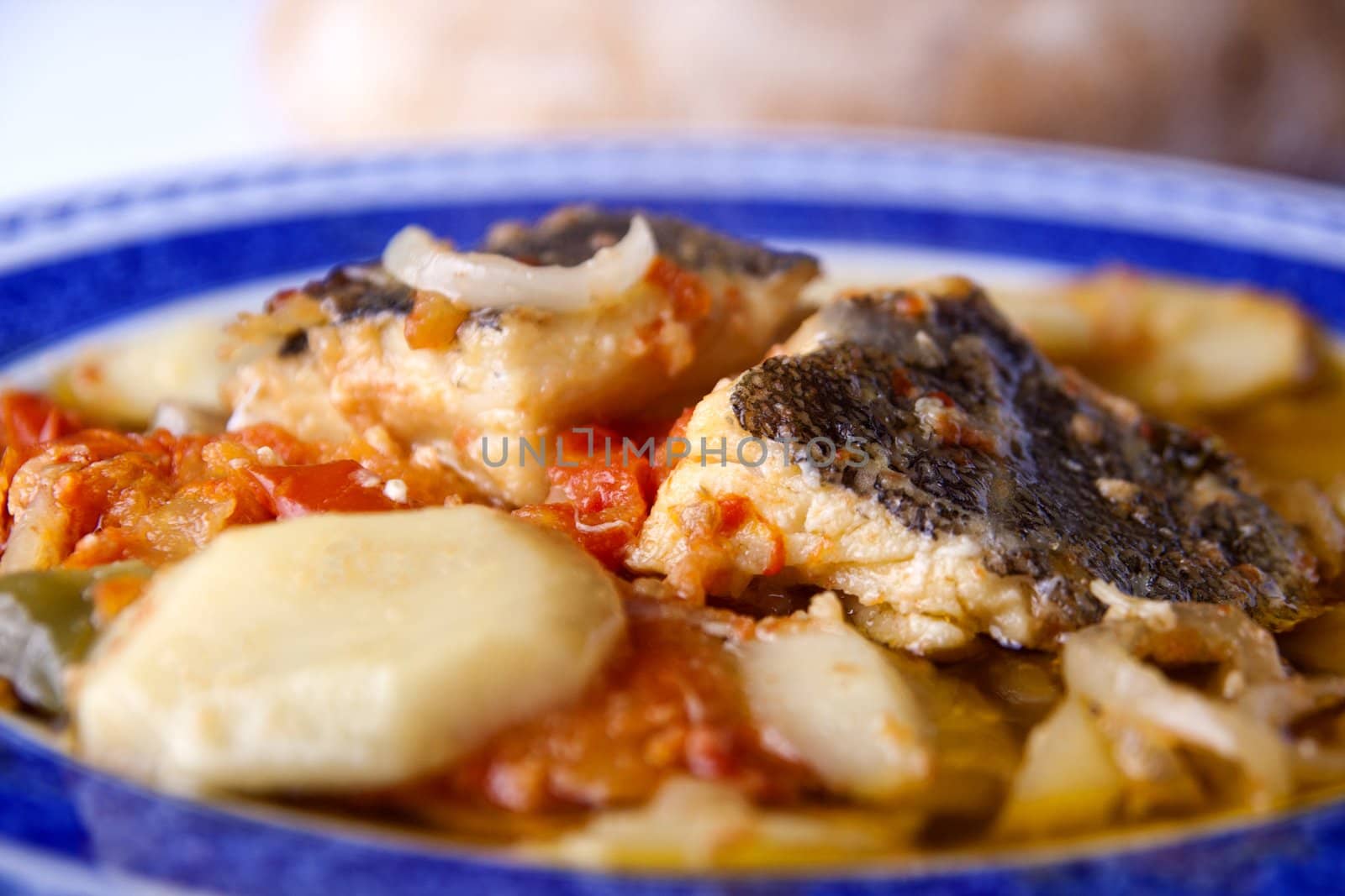 Close up view of a Portuguese meal of cod fish, potatoes and tomato.