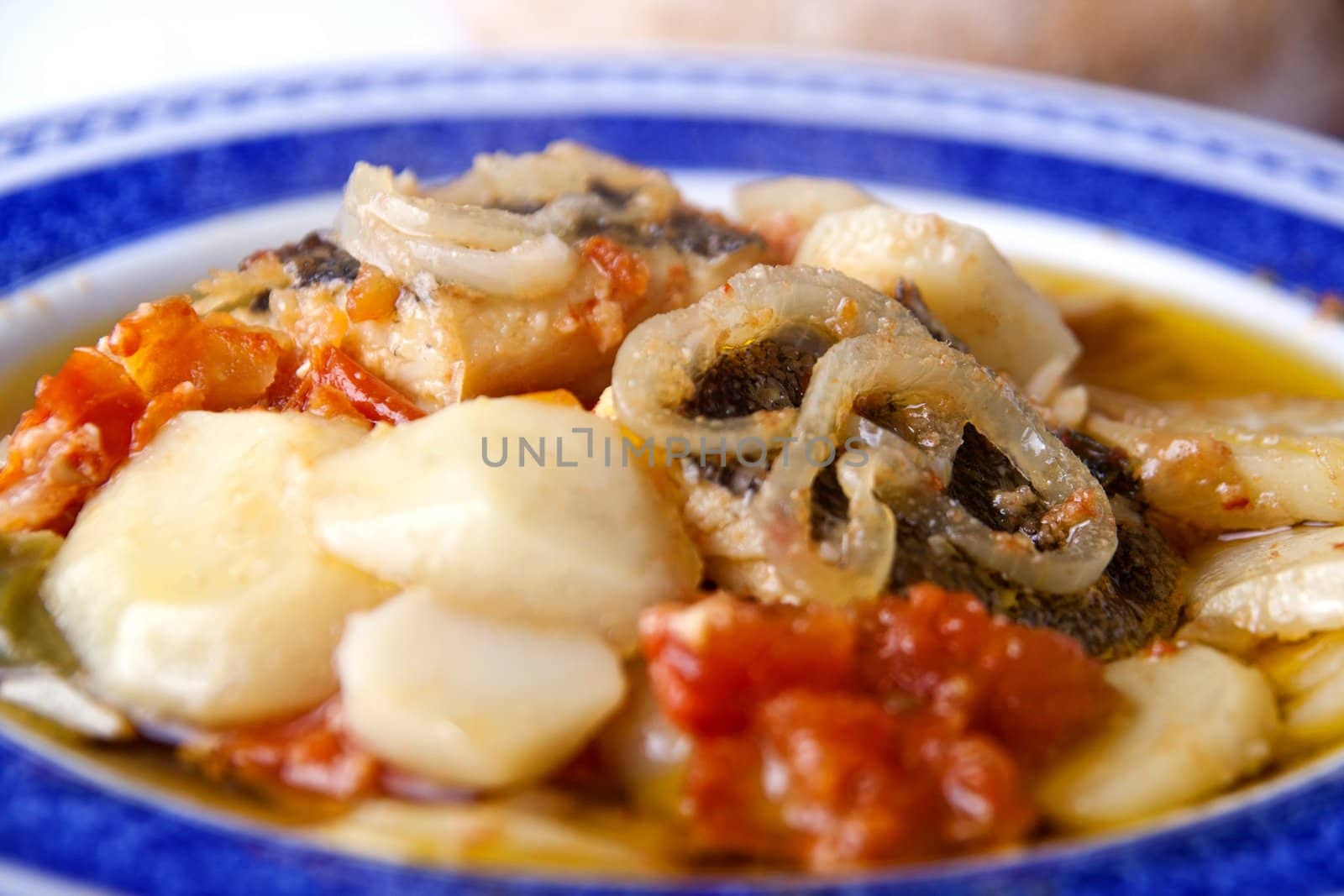 Close up view of a Portuguese meal of cod fish, potatoes and tomato.