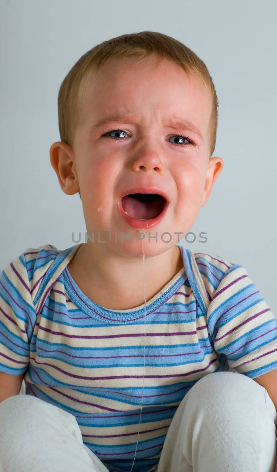 Cute crying boy on gray background