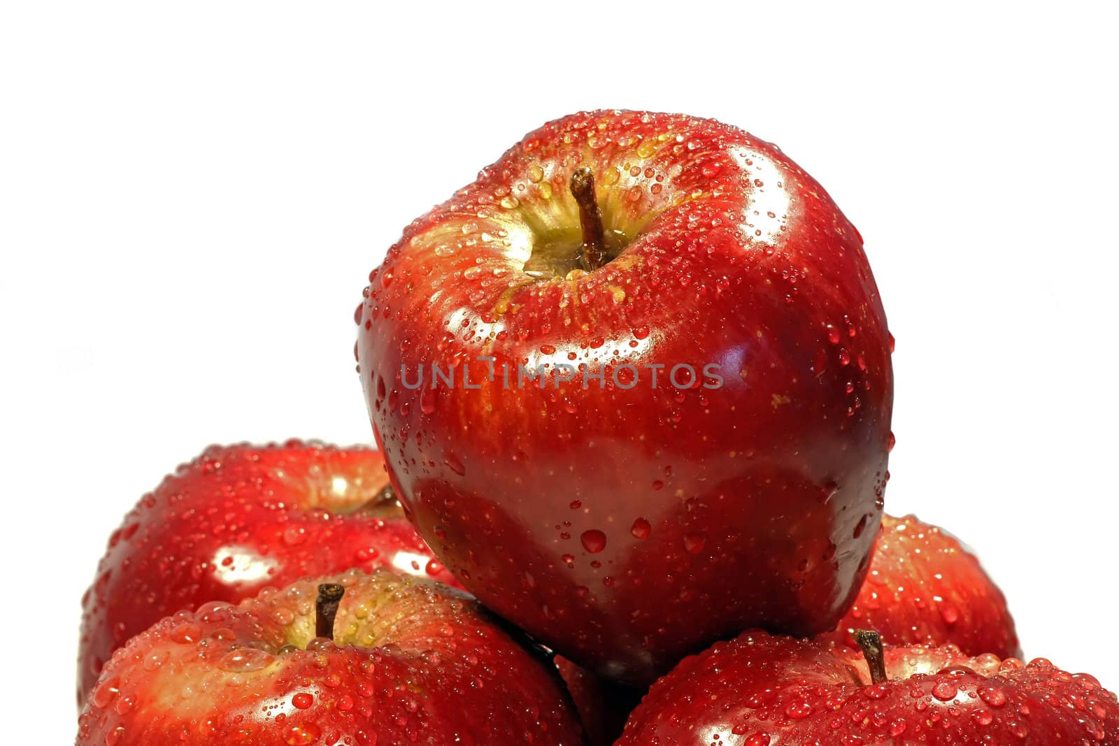 Red apple on top of others, isolated on a white background, with drops of water.