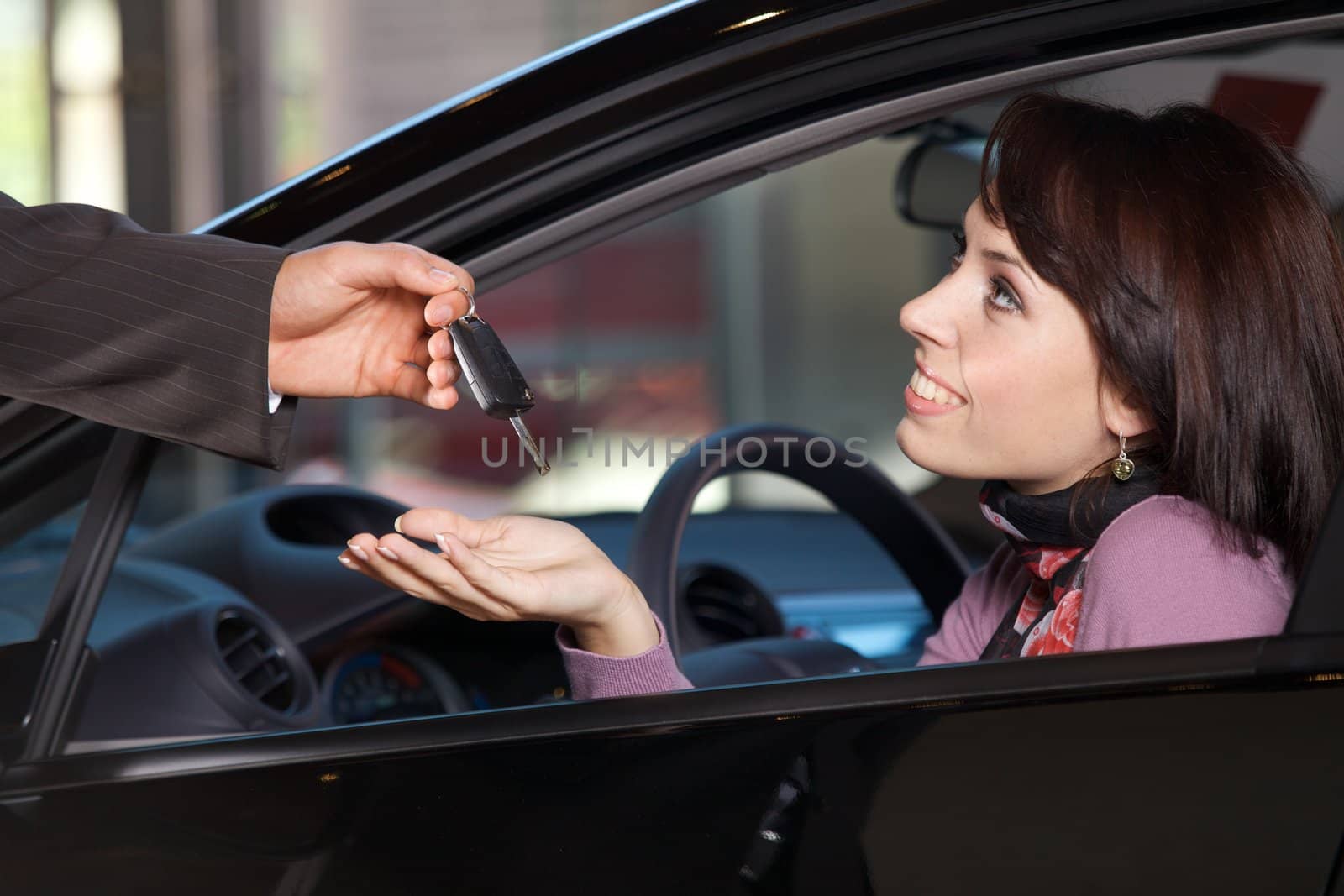 Young woman receiving the car keys from car salesman by krzysiek_z_poczty
