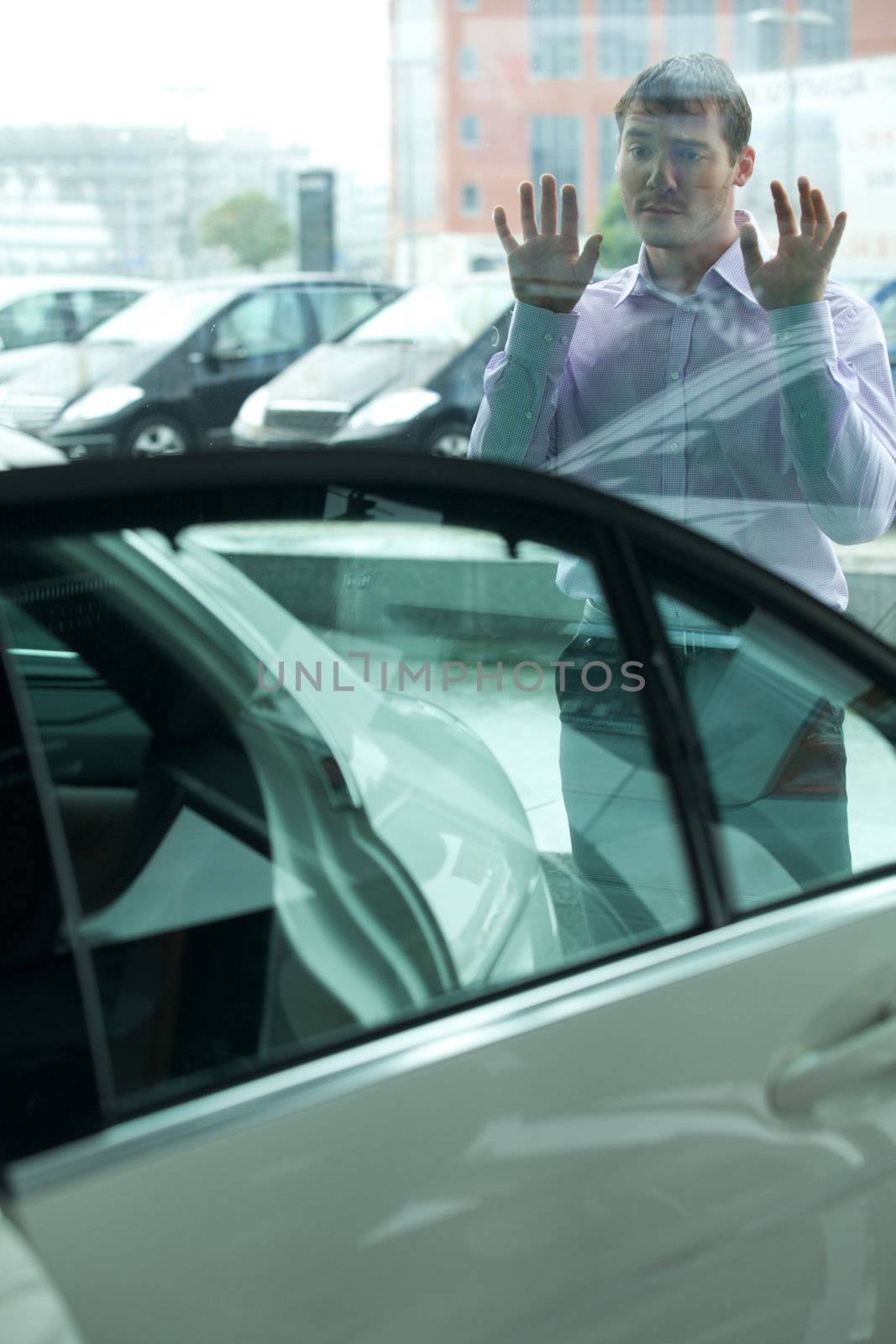 Young man curiously looking at new car in showroom
