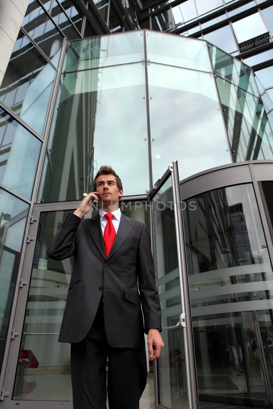 young caucasian businessman at office revolving door with cellphone