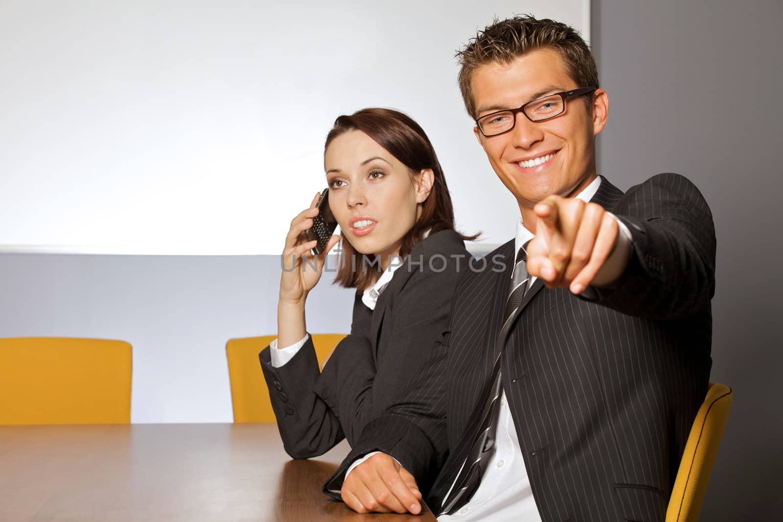 Portrait of businessman pointing while businesswoman using mobile phone
