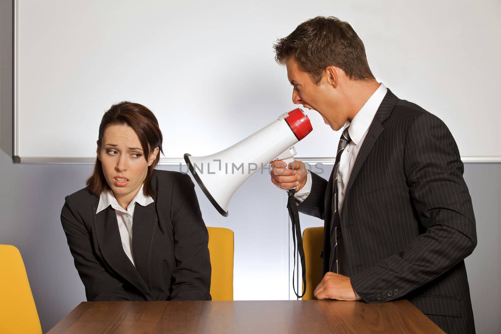 Businesswoman shouting at businessman through megaphone
