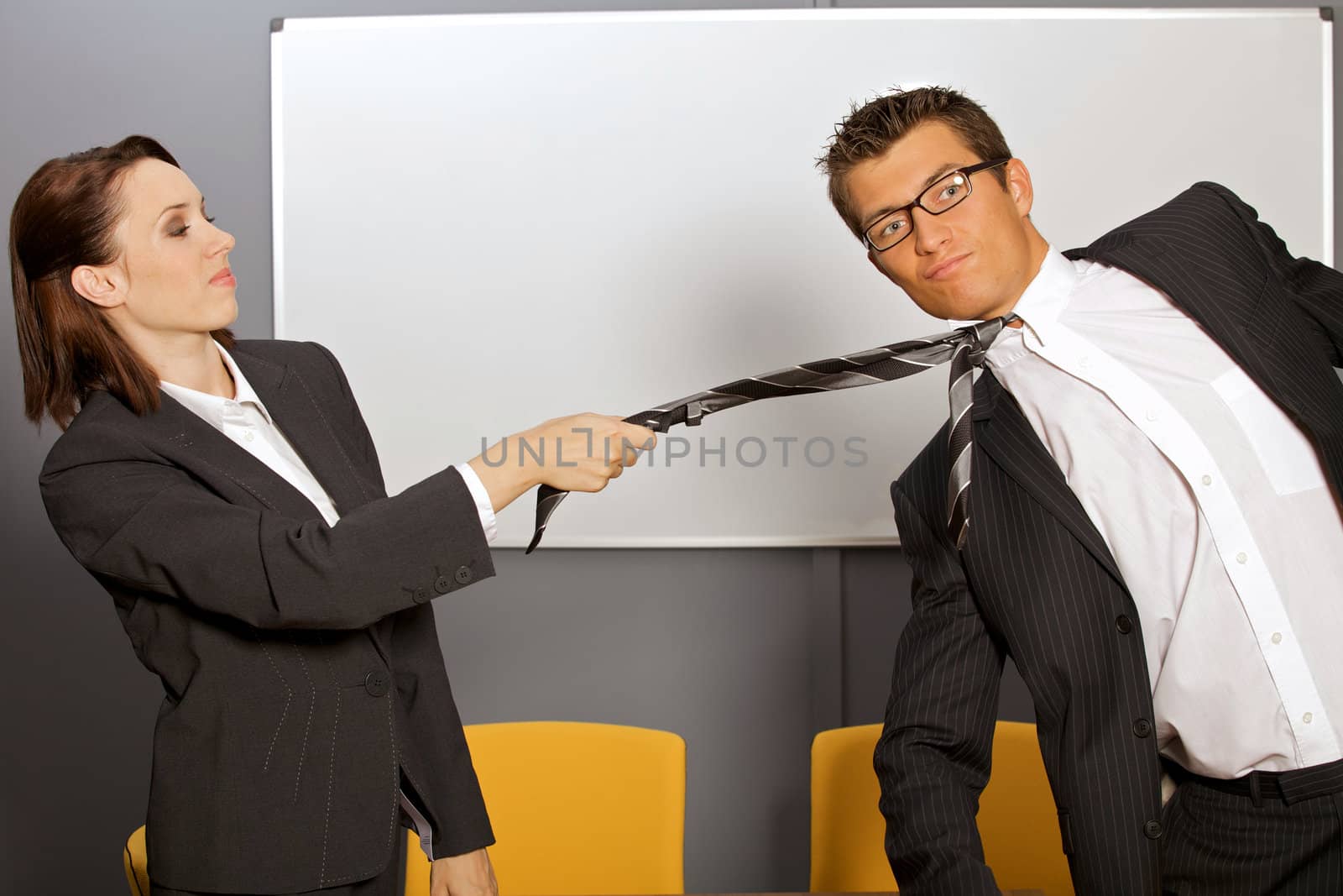 Businesswoman pulling businessman by tie