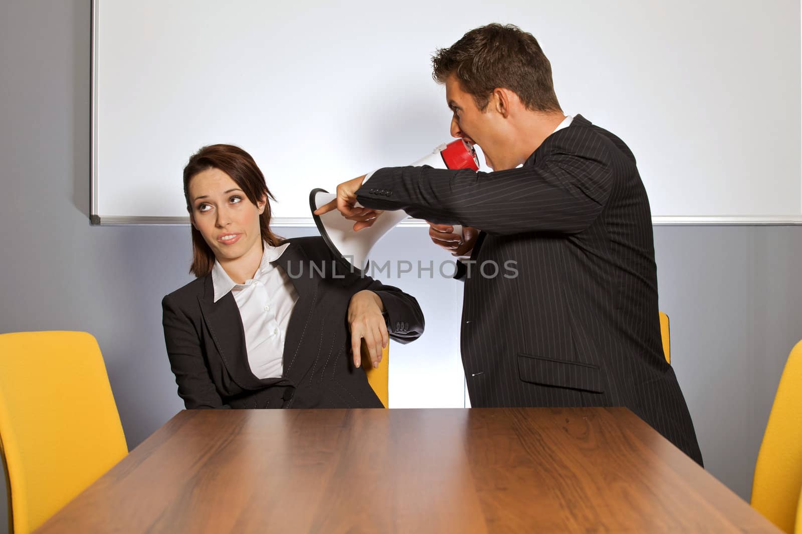 Businessman shouting at businesswoman through megaphone