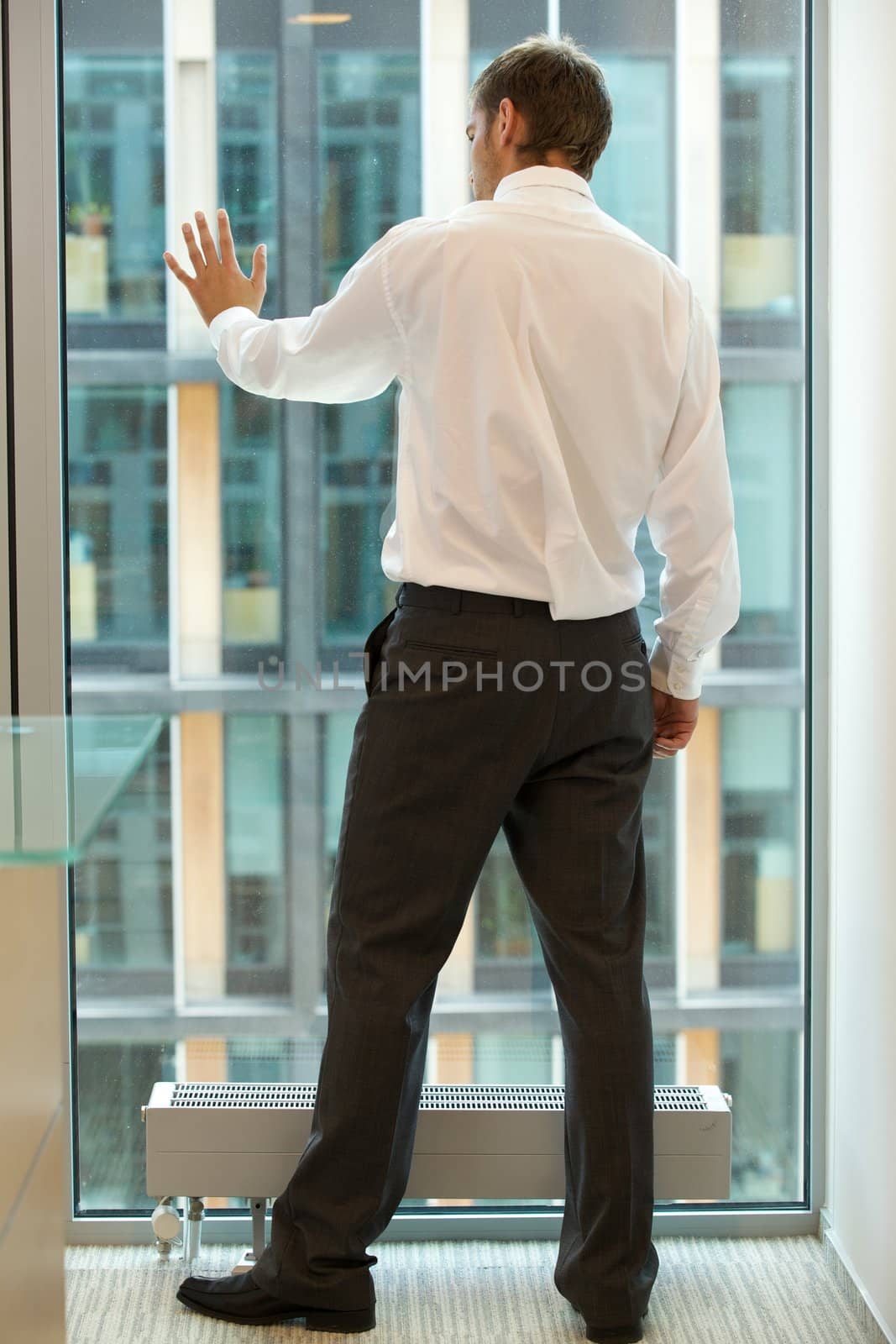 Young caucassian businessman standing against office window