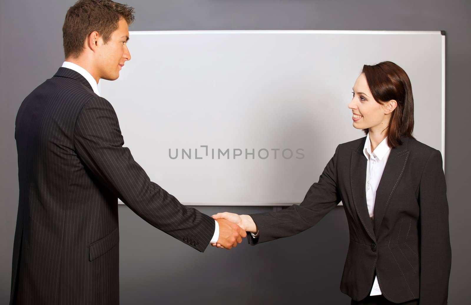 Businessman and woman shaking hands in office, smiling