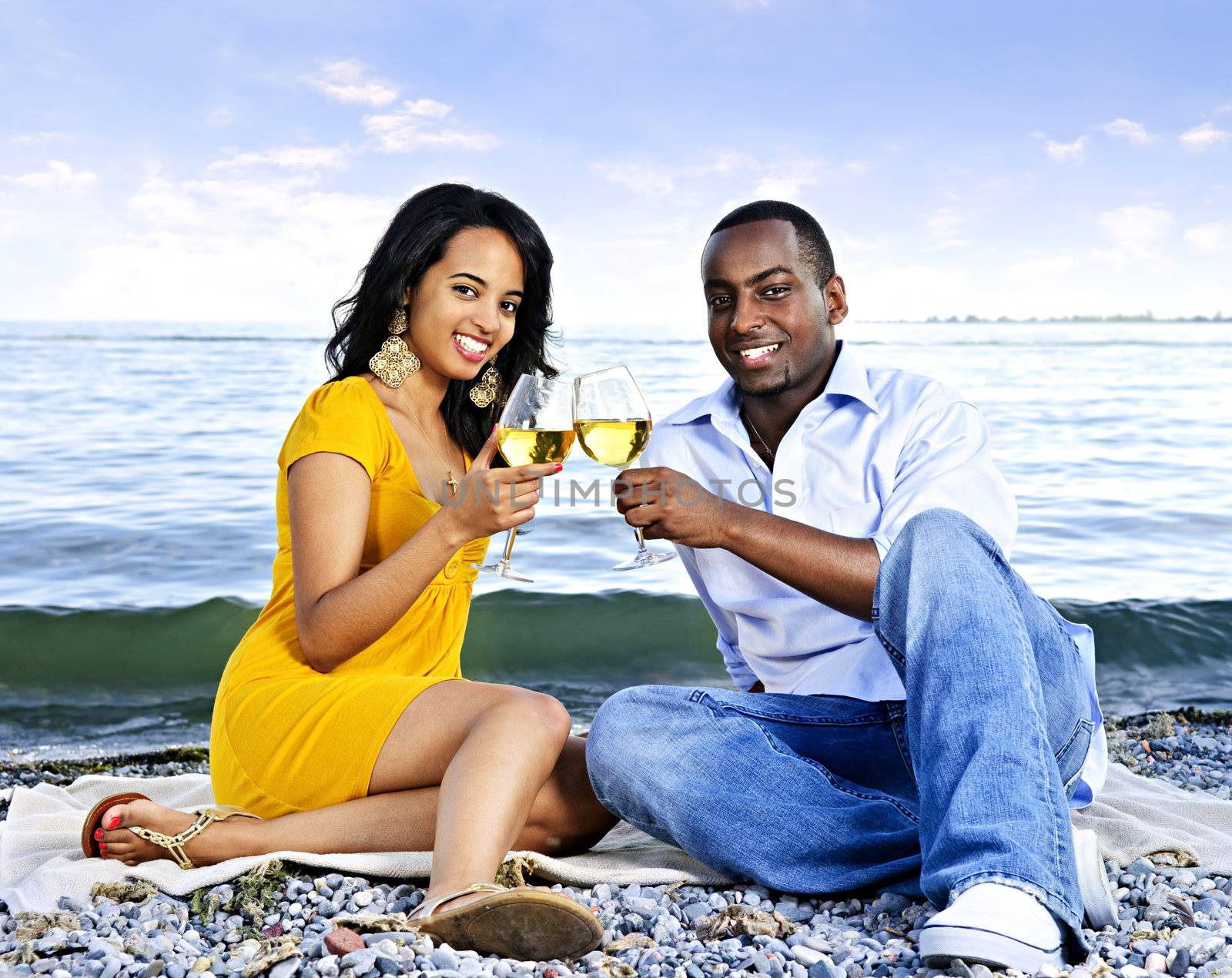 Happy couple having wine on beach by elenathewise