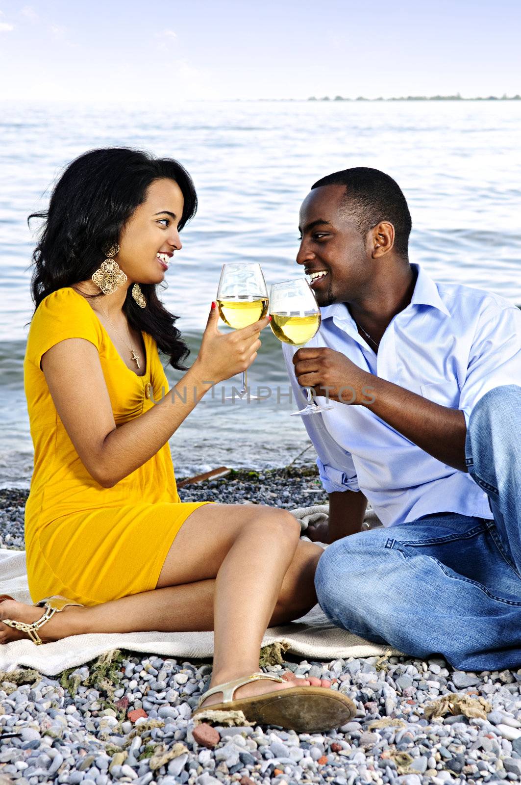 Happy couple having wine on beach by elenathewise