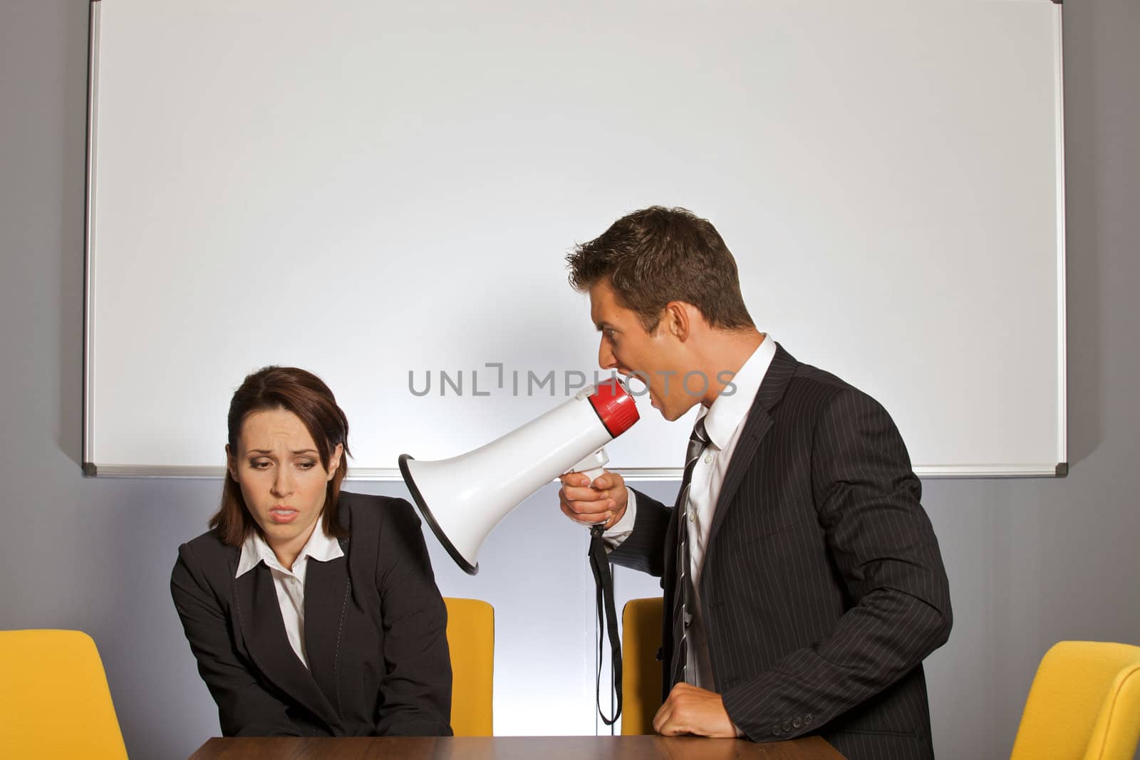 Businesswoman shouting at businessman through megaphone