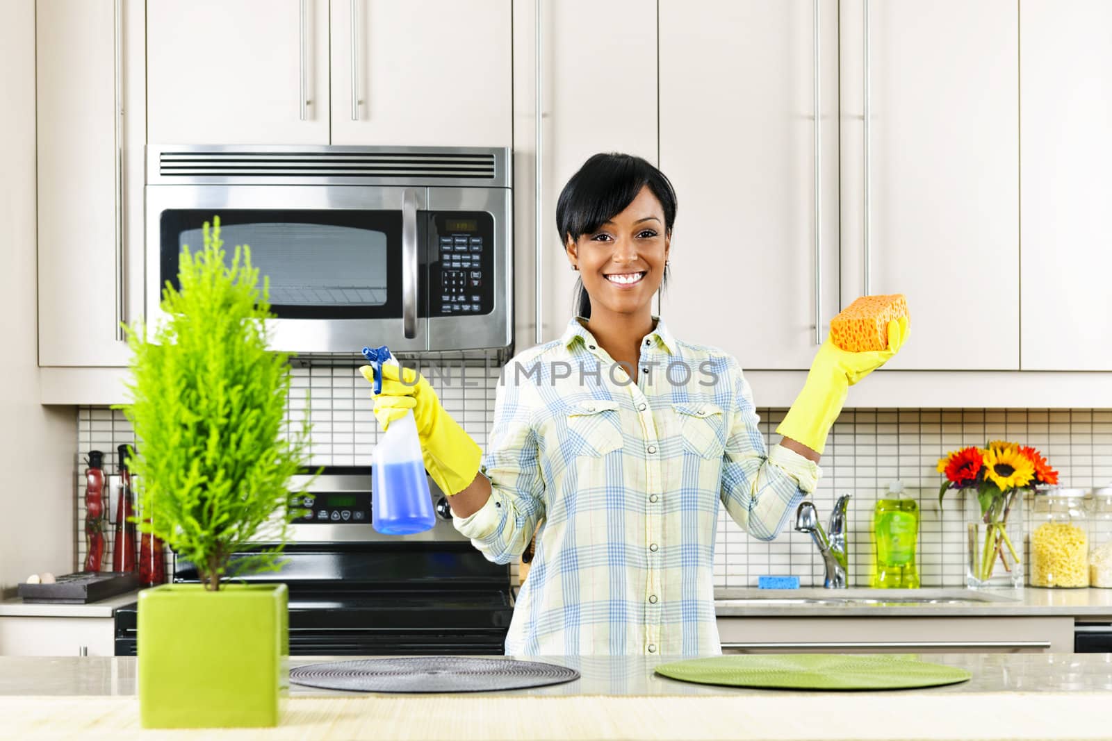 Young woman cleaning kitchen by elenathewise