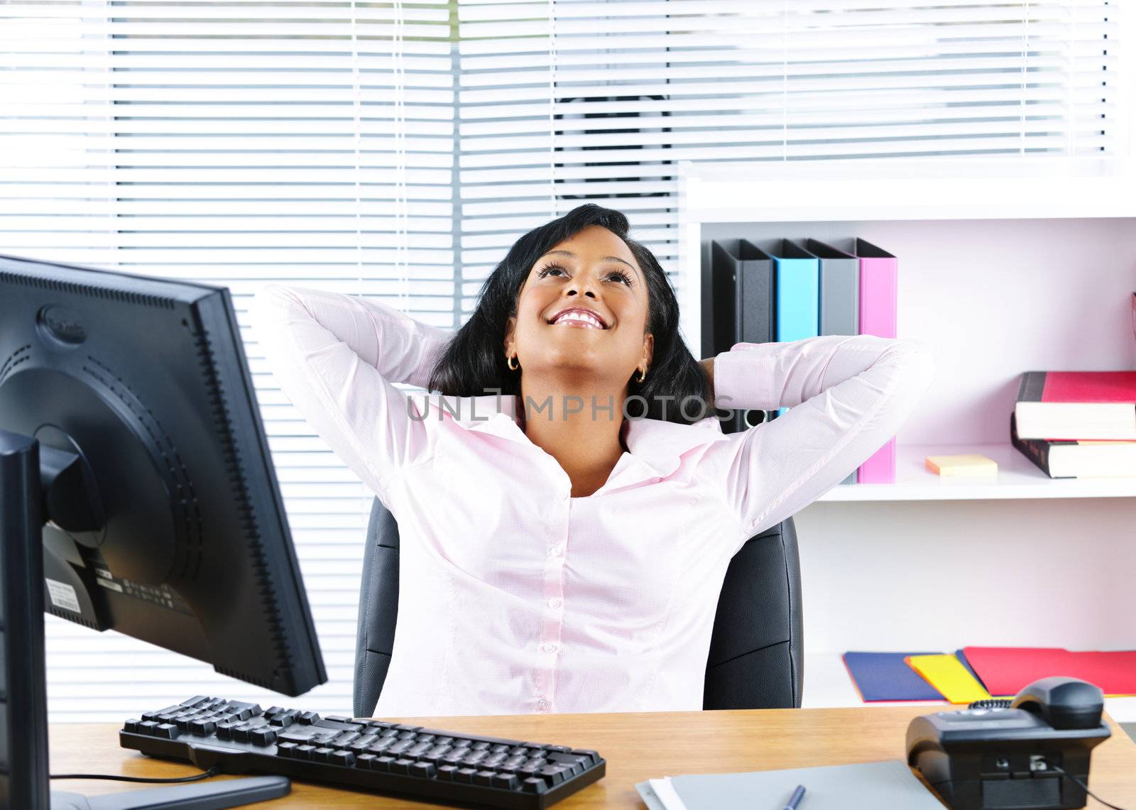 Young black business woman resting at desk in office