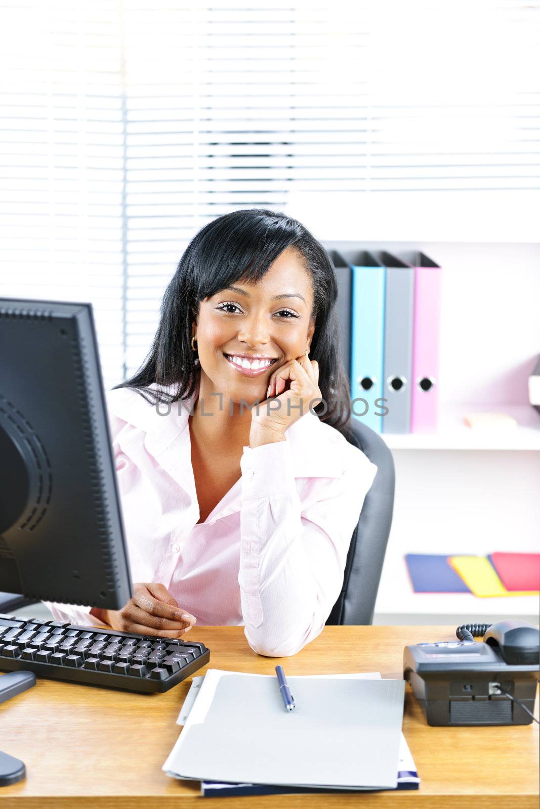 Smiling young black business woman at desk in office