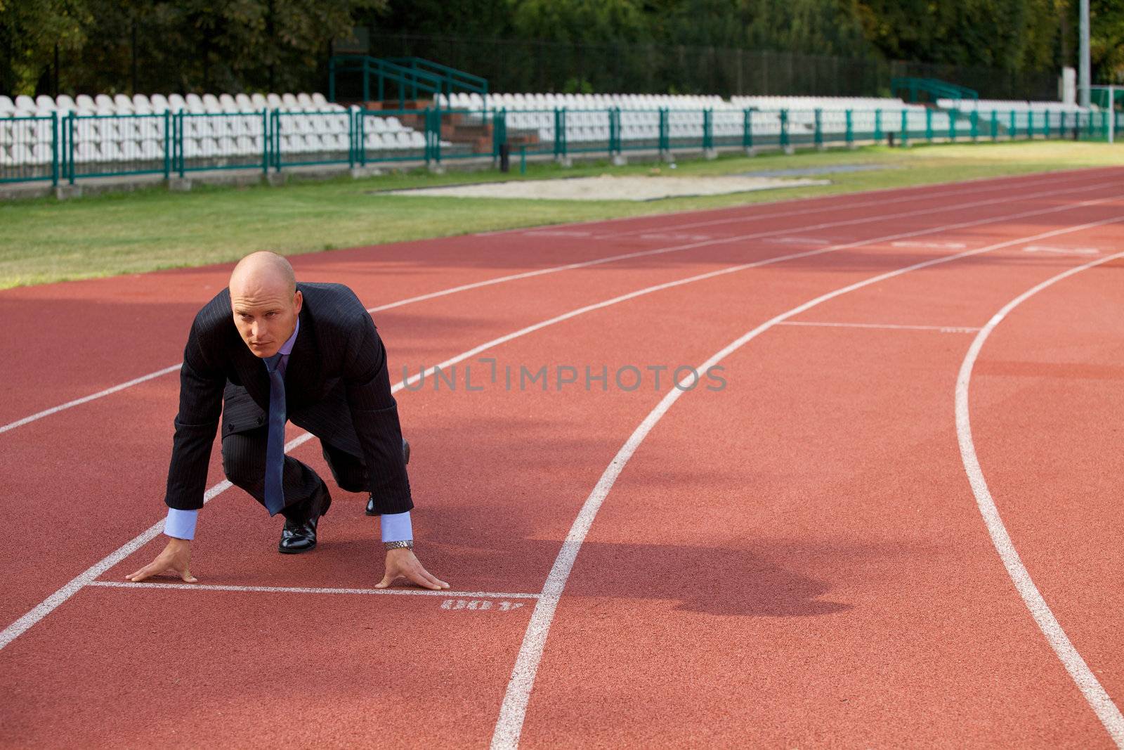 Businessman at the start line of running track
