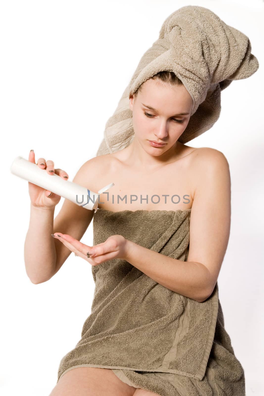 Young woman in towel on a white background with some moisterizer