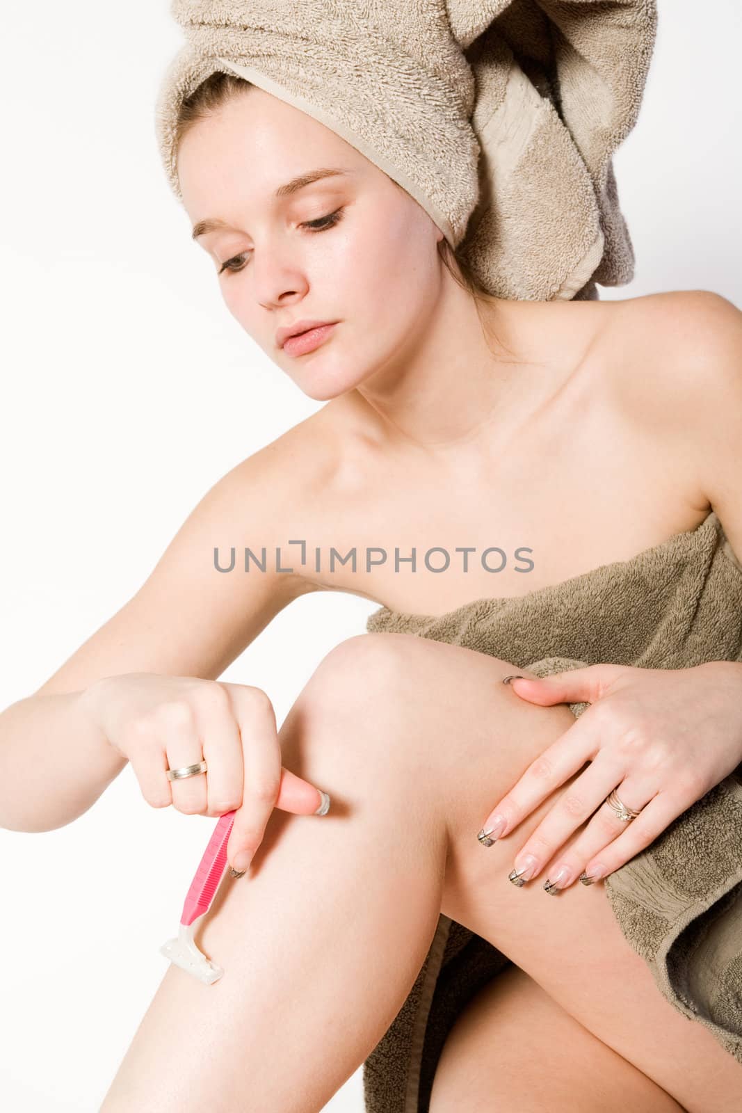 Young woman in towel on a white background shaving