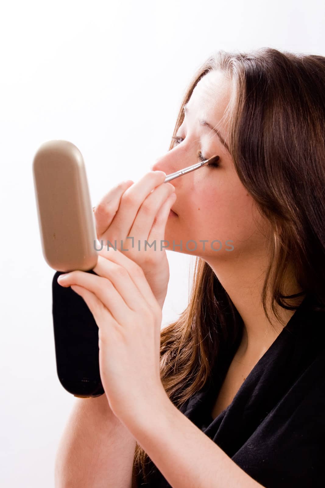 Cosmetic girl is completing her make up in the studio