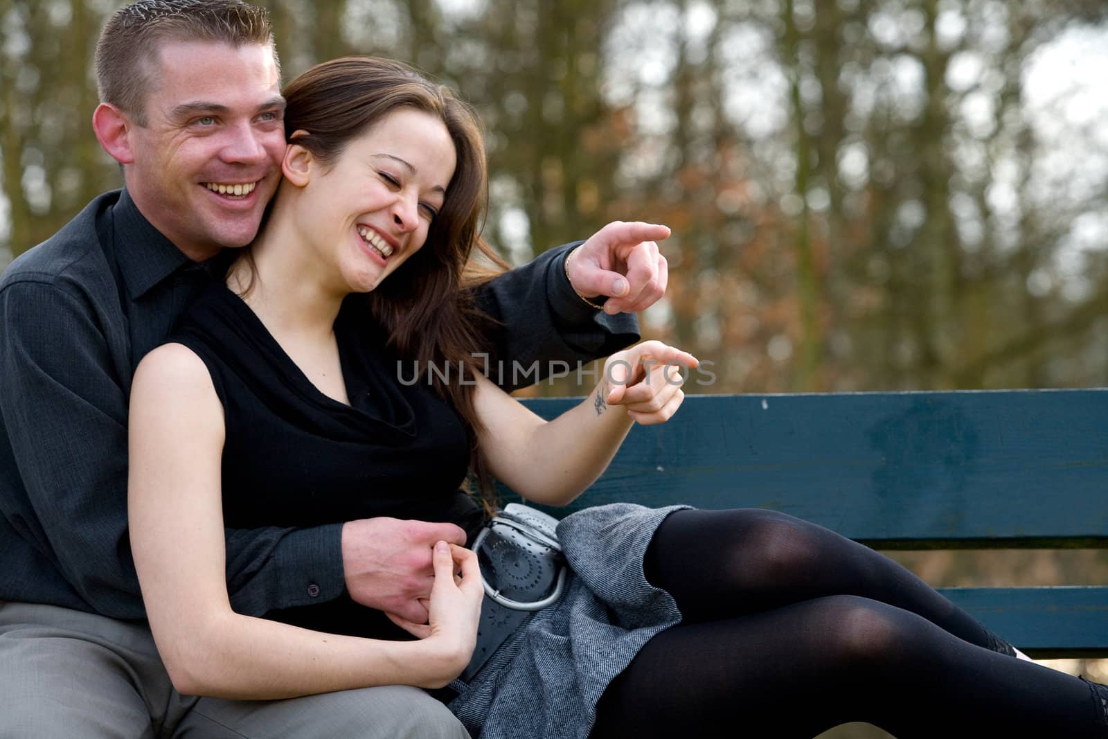 Man and girlfriend on a bench in a park having fun