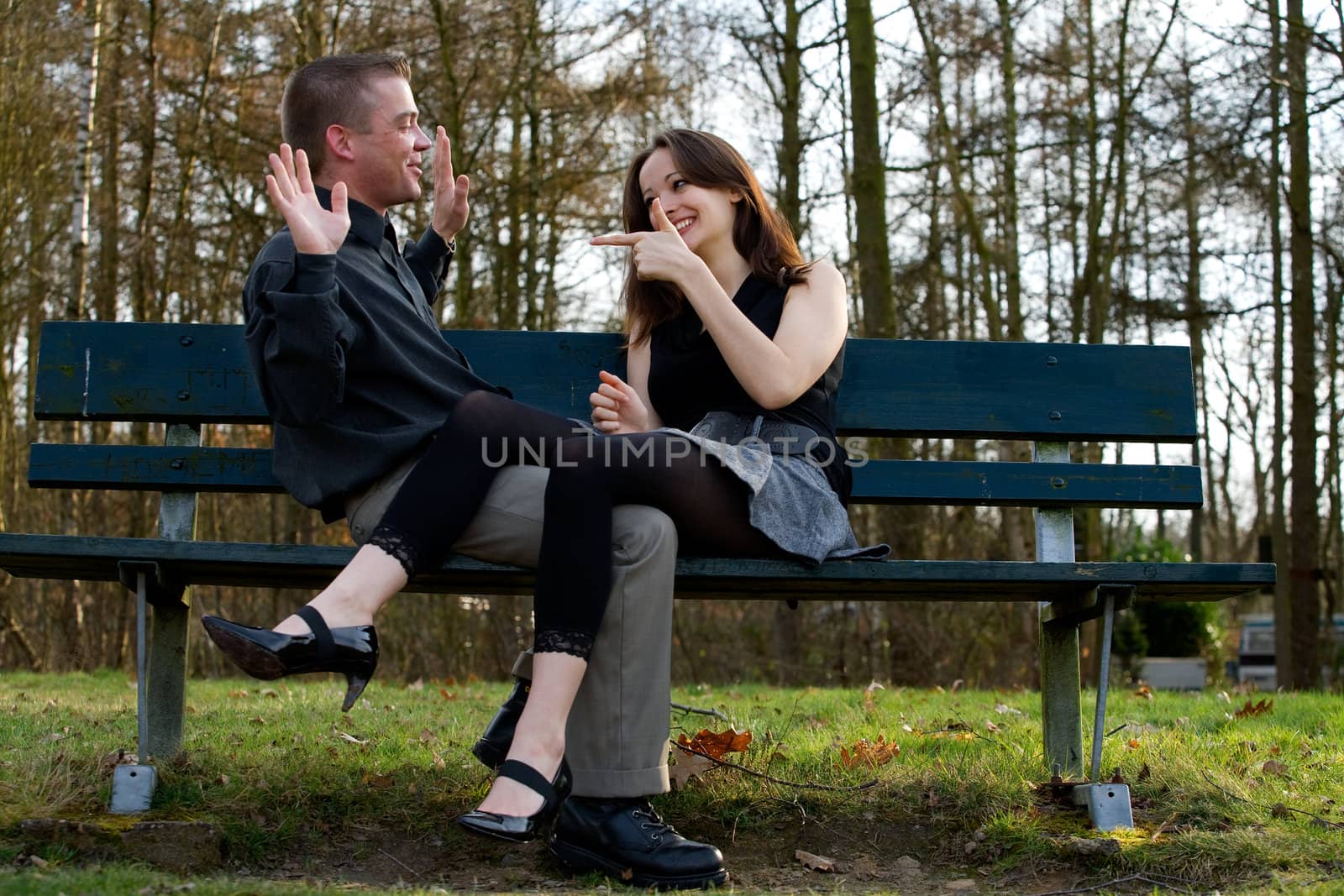 Man and girlfriend on a bench in a park having fun