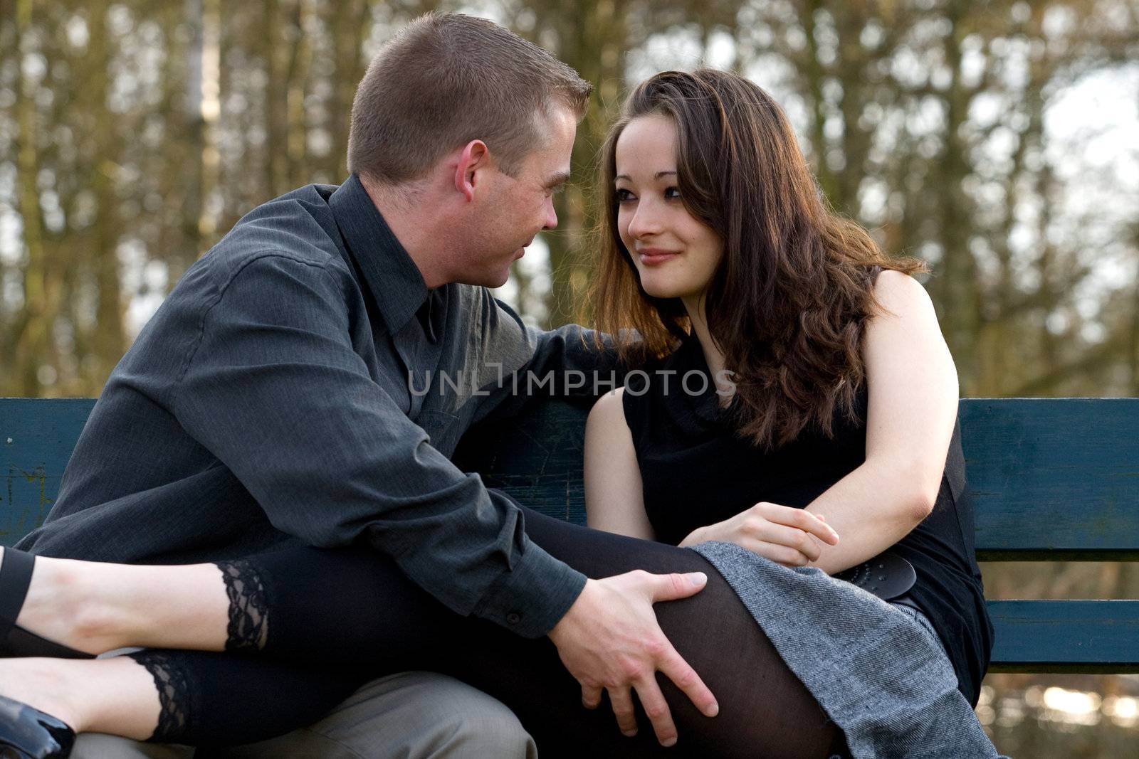 Man and girlfriend on a bench in a park tempting