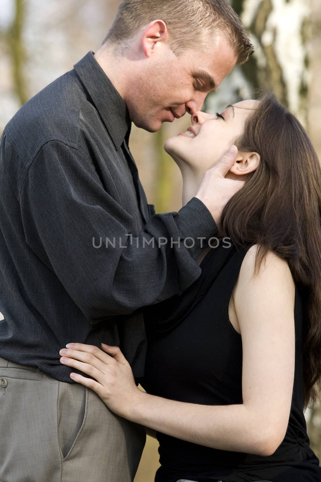 Man and girlfriend on a bench in a park tempting