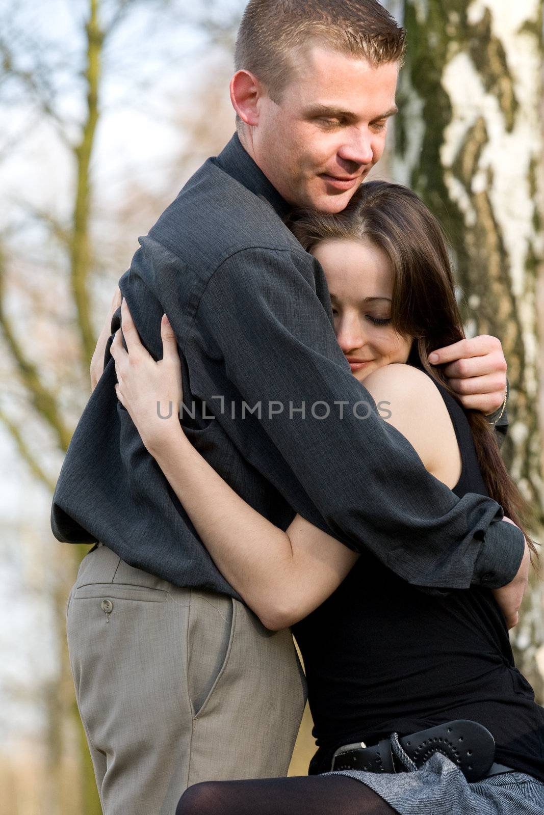 Man and girlfriend on a bench in a park caring