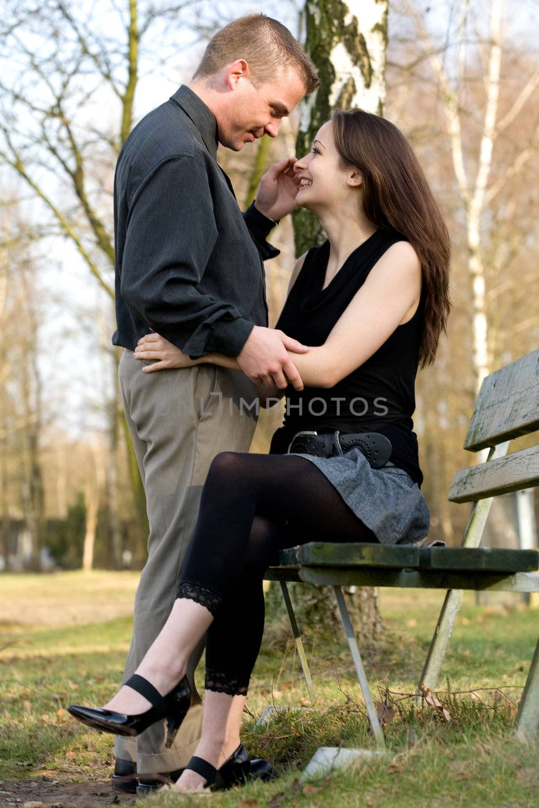 Man and girlfriend on a bench in a park having fun