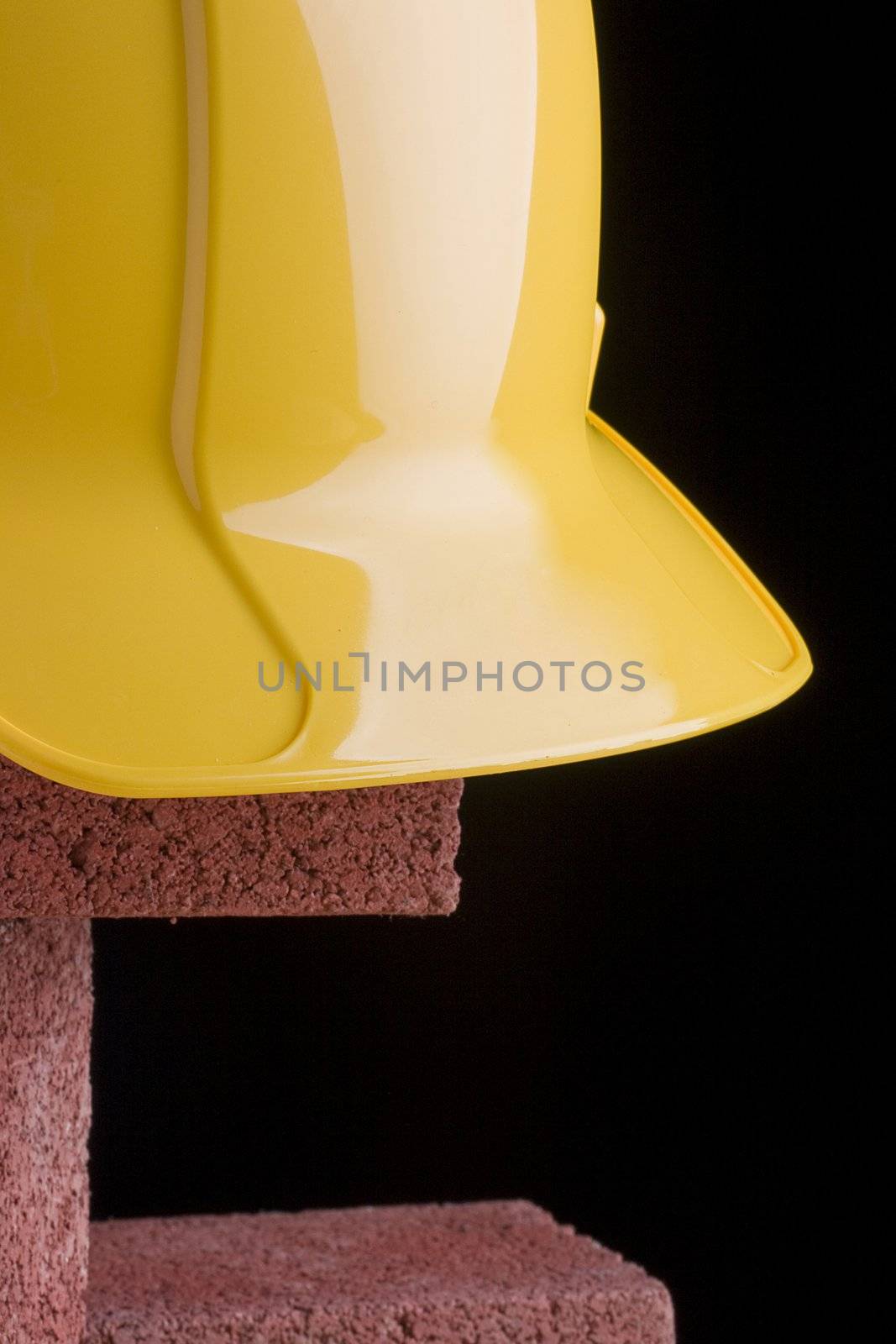 Yellow hard hat and red bricks on a black background.